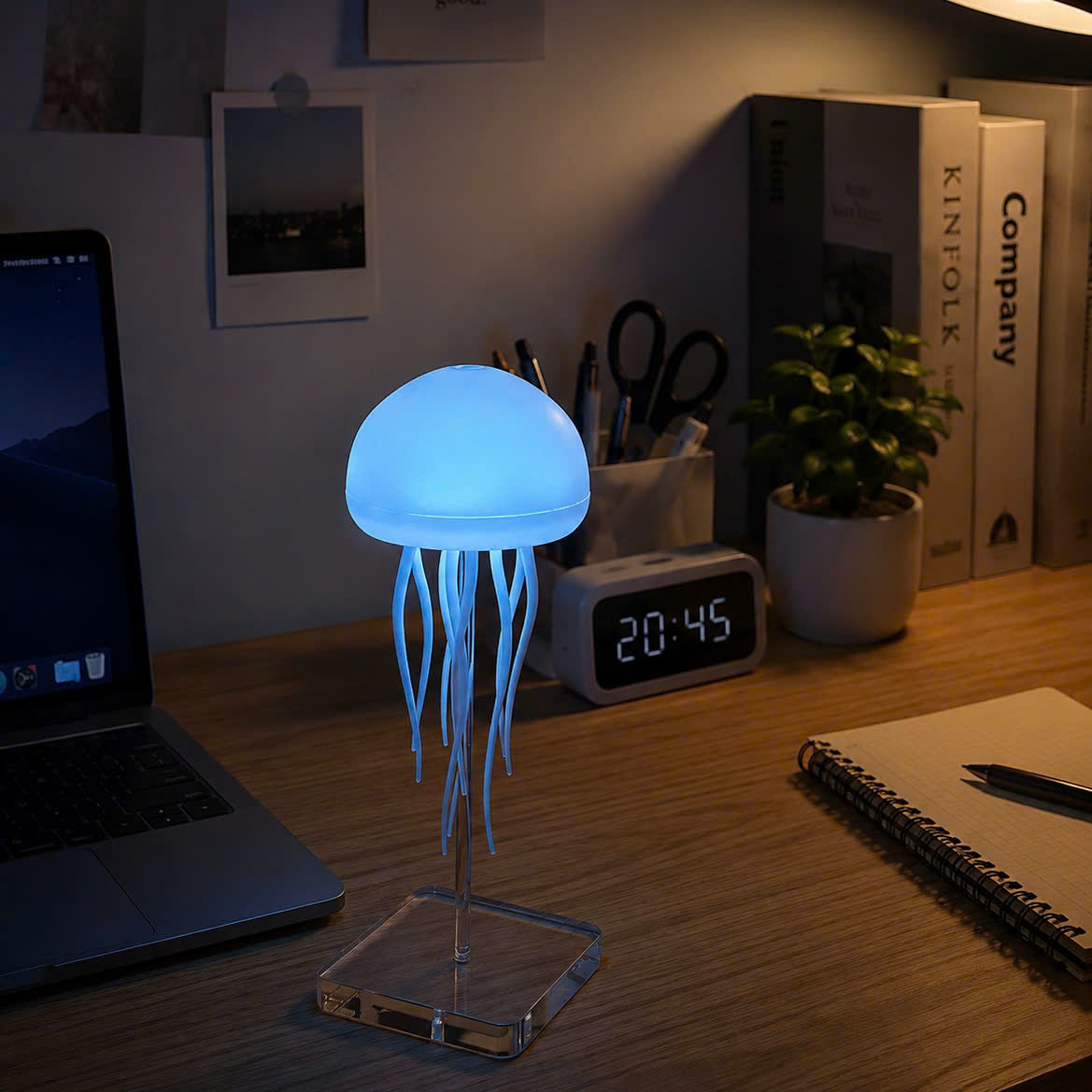 A jellyfish-shaped LED desk lamp glowing with a soft blue light, displayed on a wooden desk.